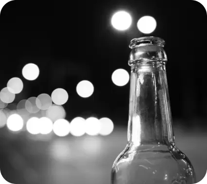 Close-up of an empty beer bottle with blurred image of traffic in the background
