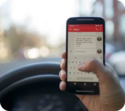 Closeup of a hand holding a mobile phone and texting while driving