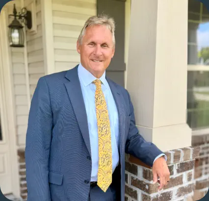 Portrait of William G. Causey, Jr. in a suit standing in front of his office